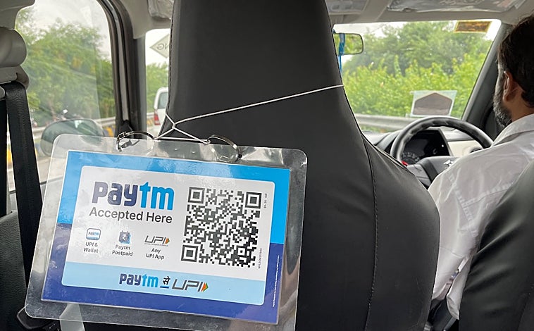 Imagen principal - En la India está cada vez más extendido el uso de las aplicaciones del móvil, como Paytm, para pequeños pagos como el taxi (imagen superior). Hasta los puestos de comida callejera o de 'chai' (té con leche) suelen tener sus códigos QR para que los clientes puedan abonar lo que consumen (arriba a la izquierda), cuyos importes aparecen reflejados en las pantallas de sus teléfonos (arriba a la derecha)