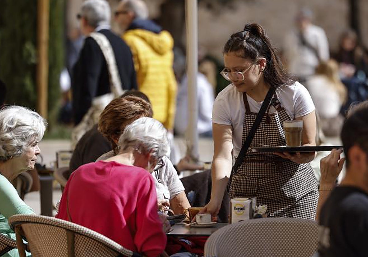 Una camarera atiende una mesa en una terraza en la ciudad de Valencia