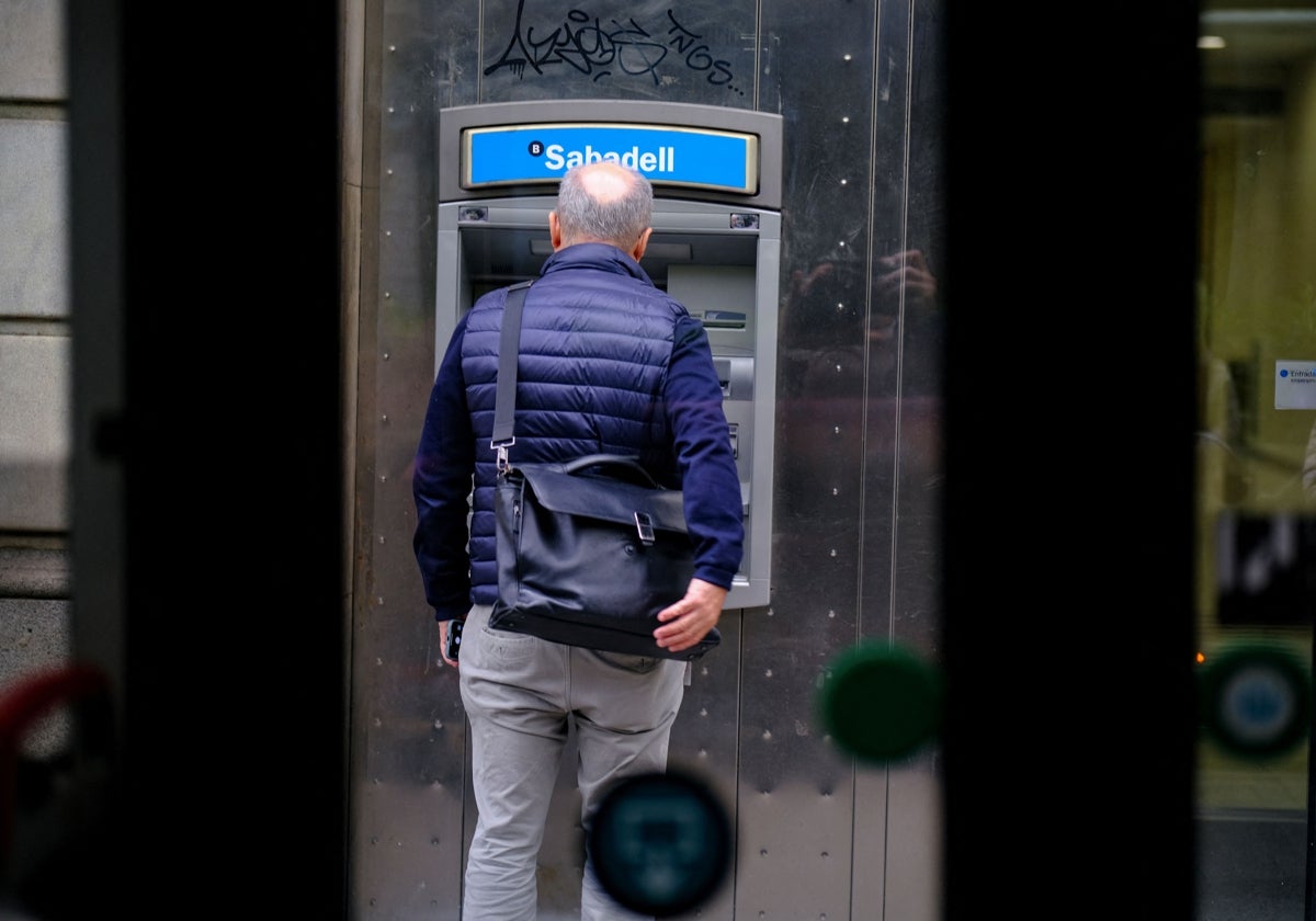 Un hombre frente a un cajero del Banco Sabadell