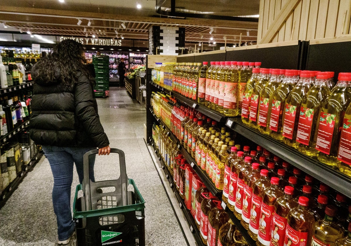 Una mujer pasa por un lineal con botellas de aceite de oliva en un supermercado