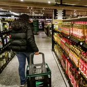Una mujer pasa por un lineal con botellas de aceite de oliva en un supermercado