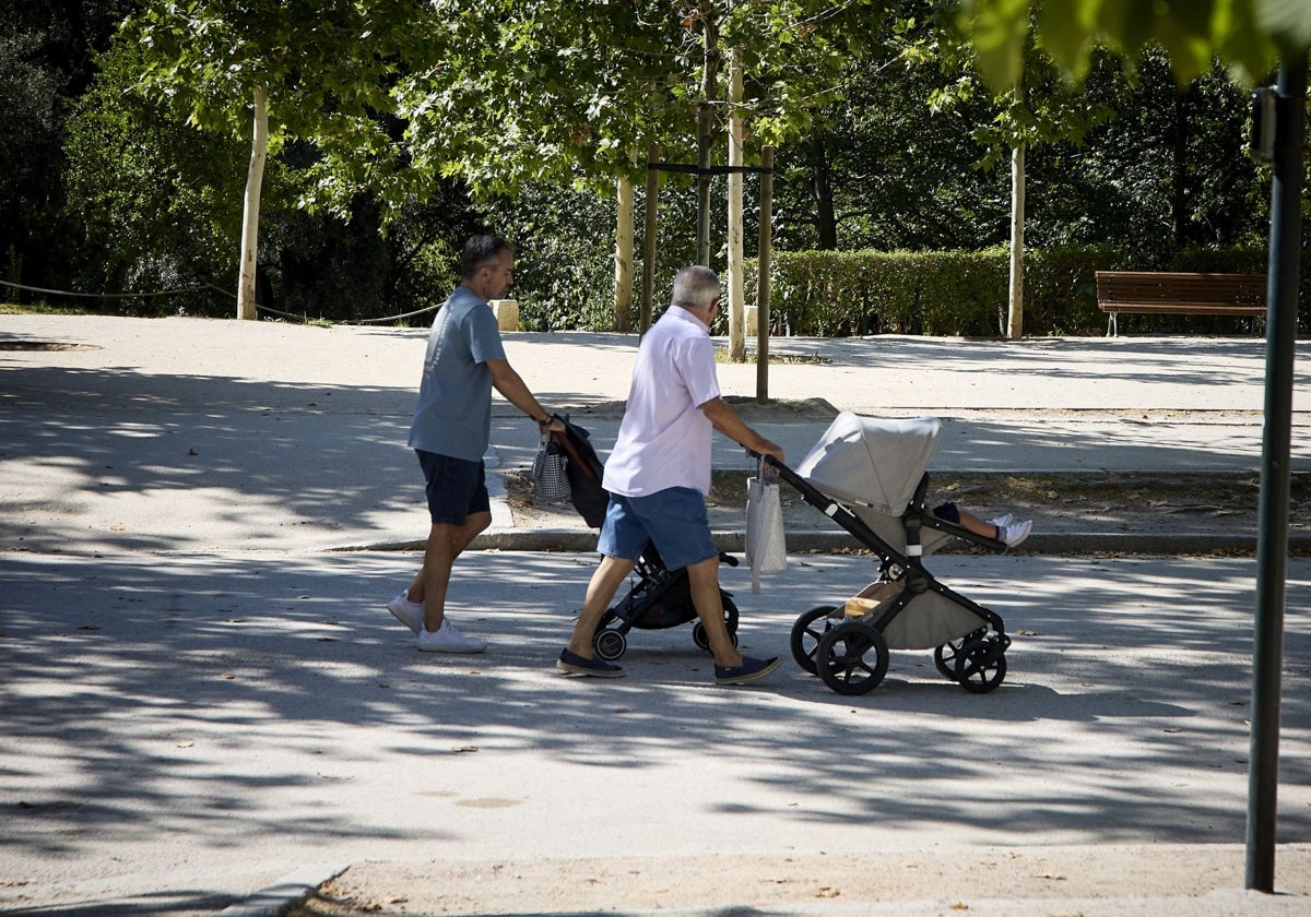 Dos padres llevando a sus bebés en el carrito por el parque de El Retiro (Madrid)