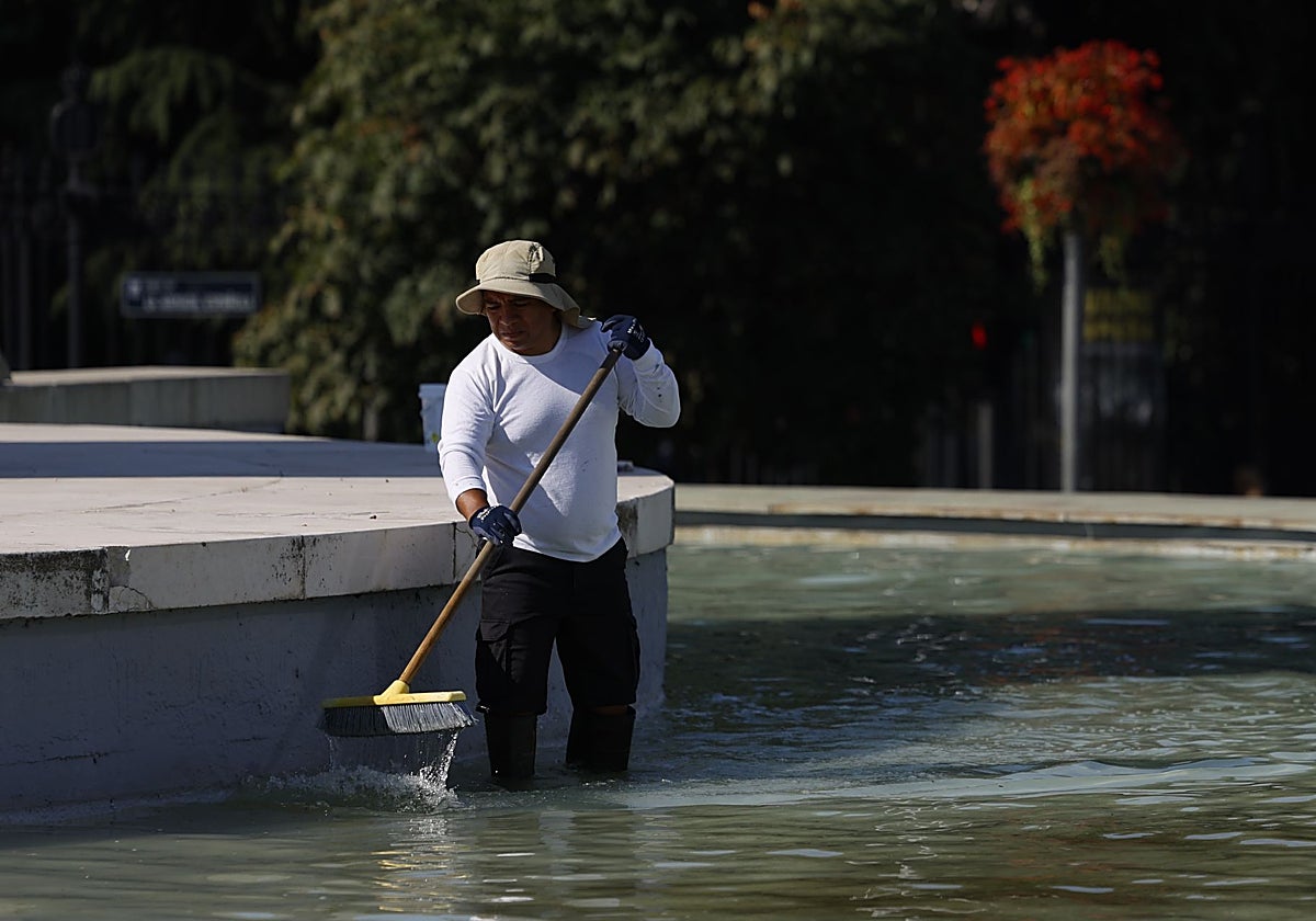 Un trabajador limpia el fondo de una fuente