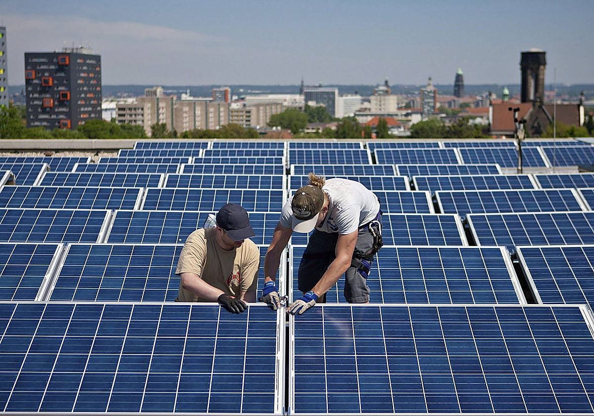 Unos operarios instalan paneles solares en un edificio