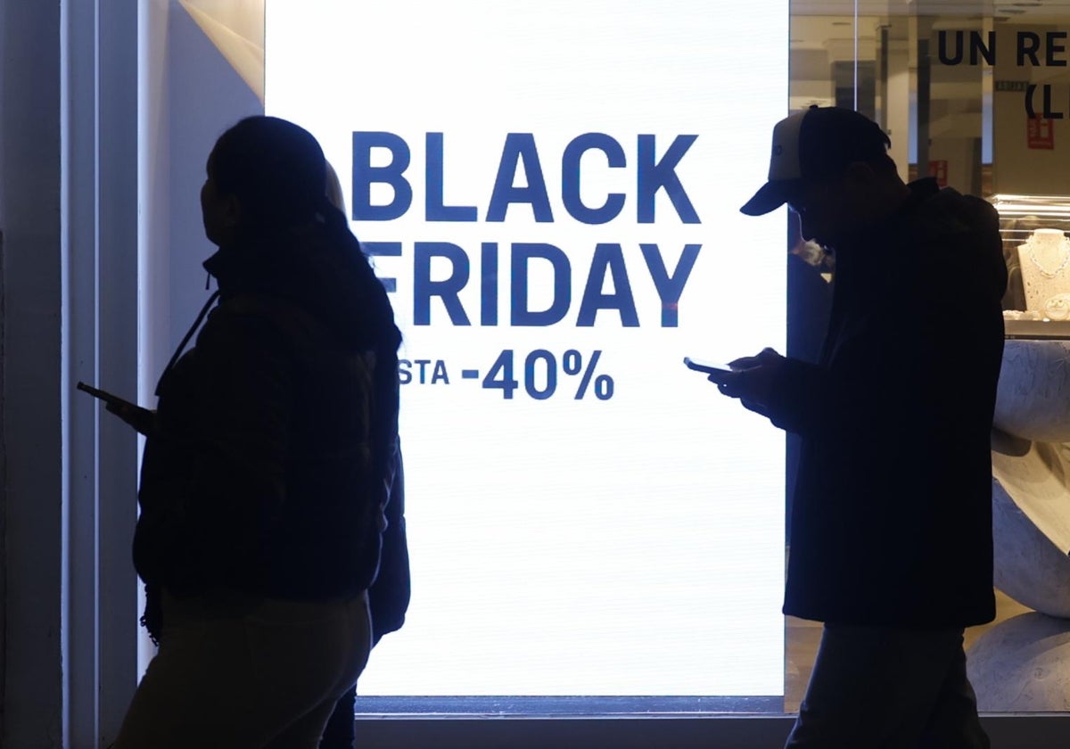 Viandantes pasando frente a un cartel de Black Friday