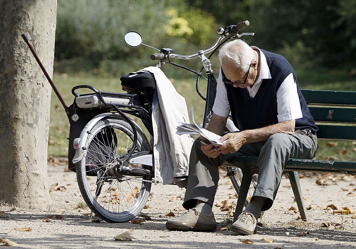 Un jubilado leyendo en un parque.