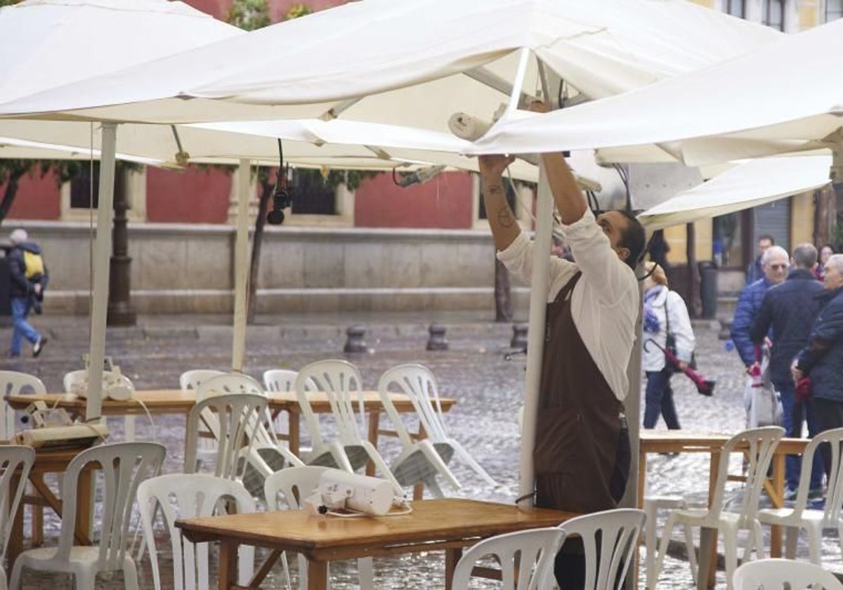 Camarero recogiendo una terraza en un bar de Sevilla.