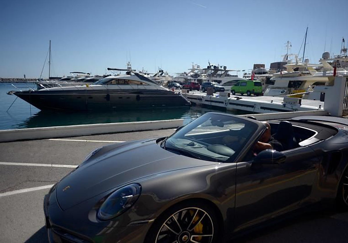Un hombre conduce un deportivo por Puerto Banús, en Marbella