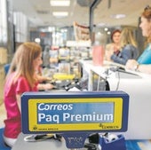 Una empleada de Correos atiende a una clienta en una oficina postal