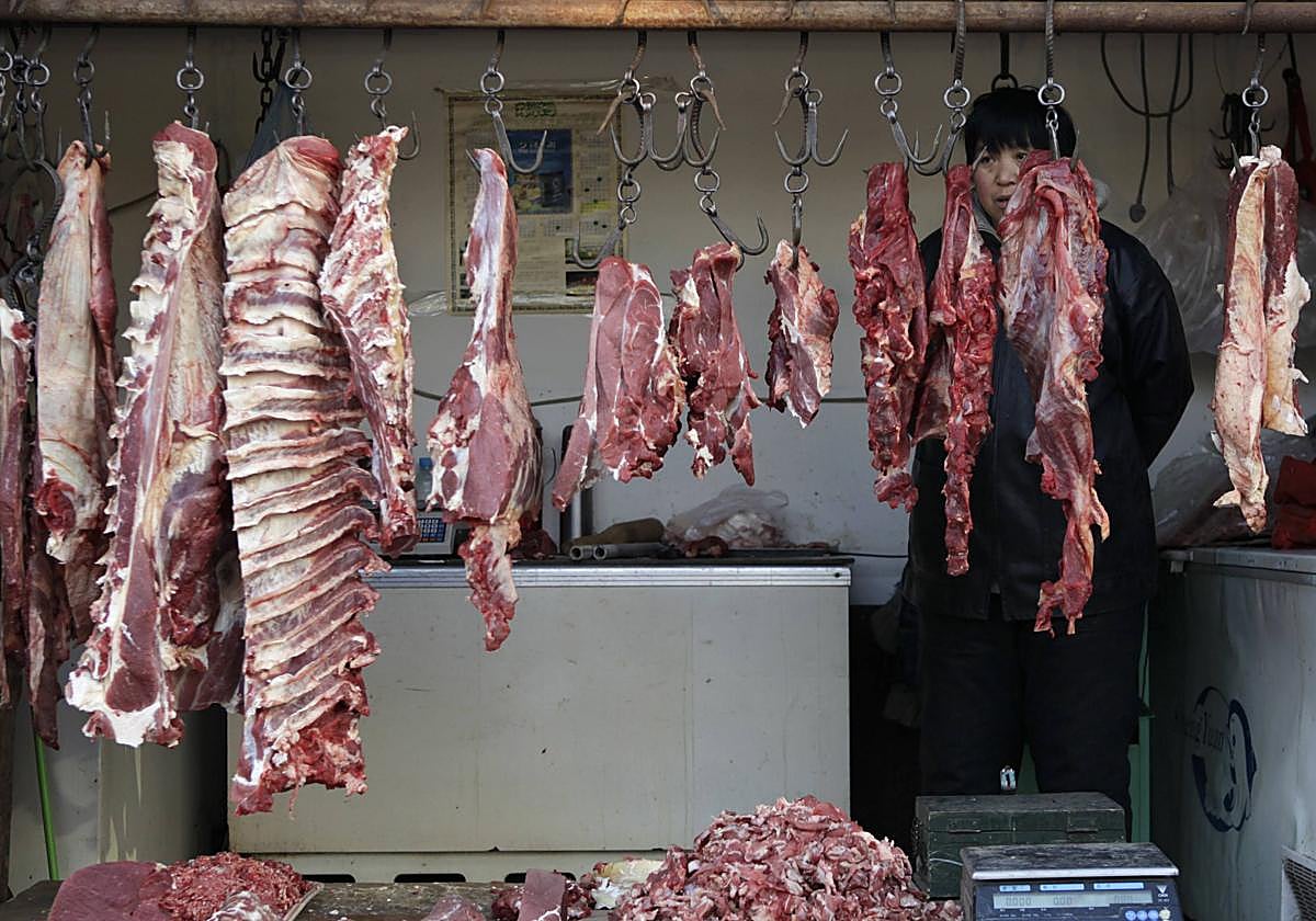 Una vendedora de carne de vacuno espera a los clientes en su puesto de un mercado de Pekín (China)