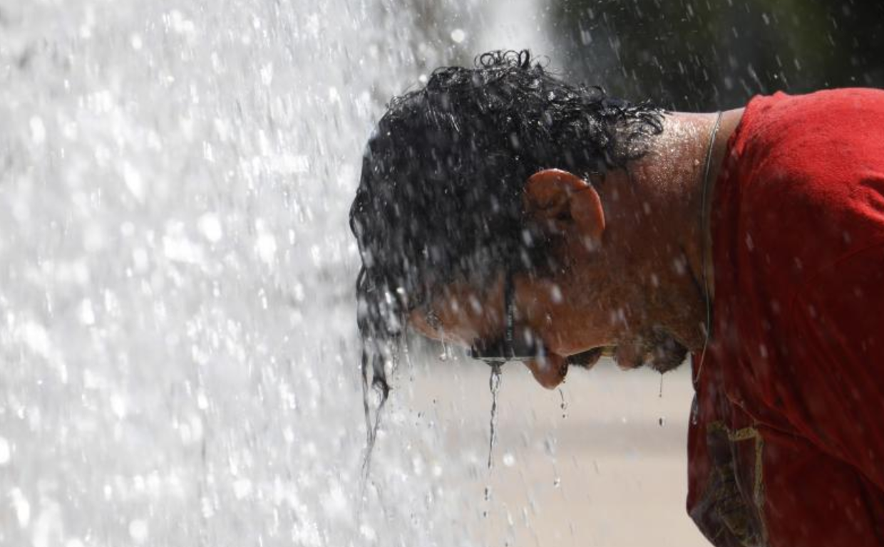 Un hombre se refresca en una fuente del centro de Córdoba