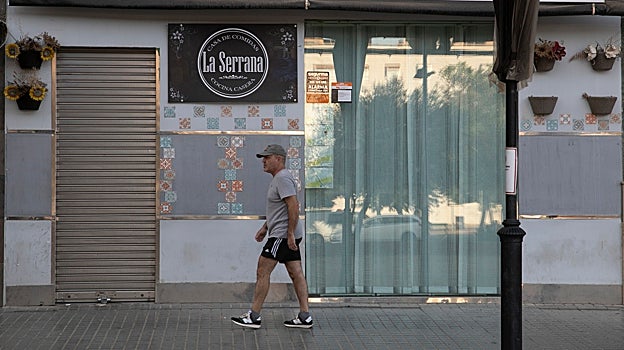 Un hombre pasa delante de un local de restauración cerrado