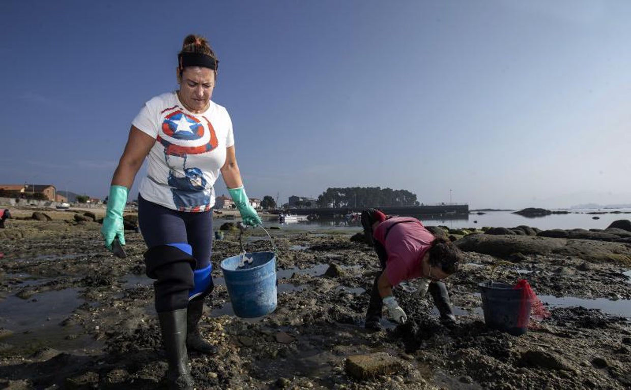 Lourdes, junto a otra mariscadora, ayer en la playa de A Sapeira