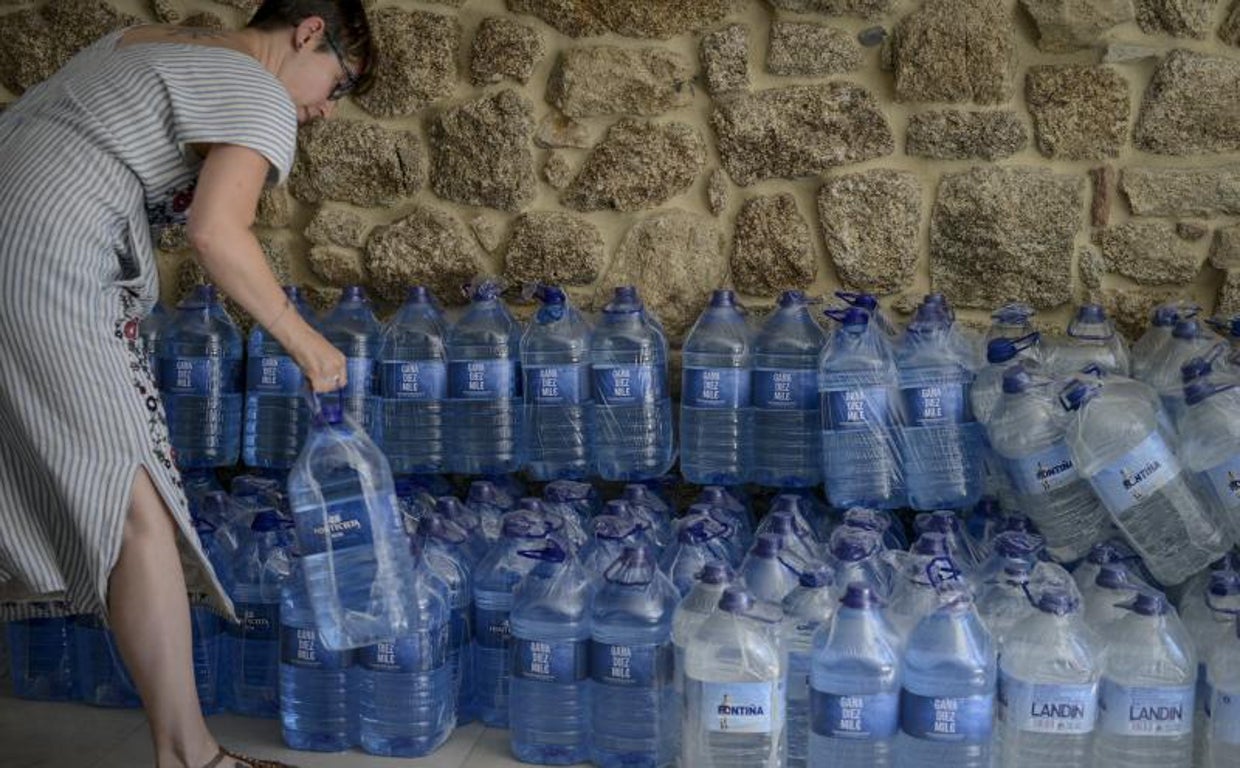 Una vecina de Ribadavia coge agua embotellada facilitada por el Concello para los núcleos afectados por las restriciones