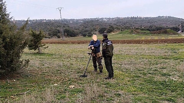 Agente forestal llamando la atención a un hombre con un detector de metales