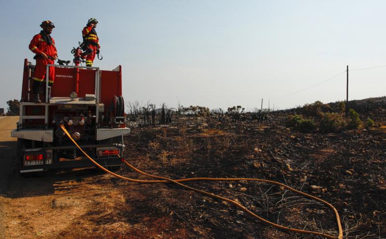 Bomberos junto a una zona arrasada por el incendio forestal de Vall d'Ebo