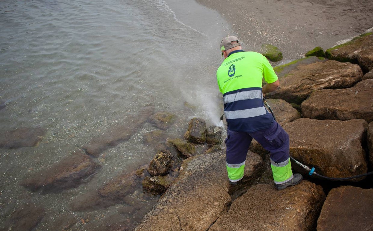 Un operario se afana en retirar el combustible adherido a las rocas