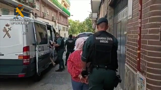 Una de las detenidas es conducida a un furgón por un agente de la Usecic