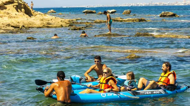 Bañistas en una pequeña embarcación disfrutan del agua en Tabarca