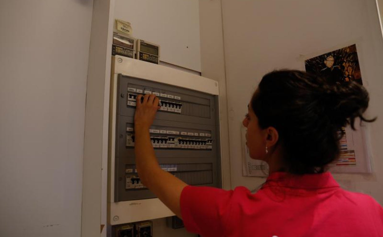 Una mujer bajando los plomos del cuadro eléctrico de su negocio
