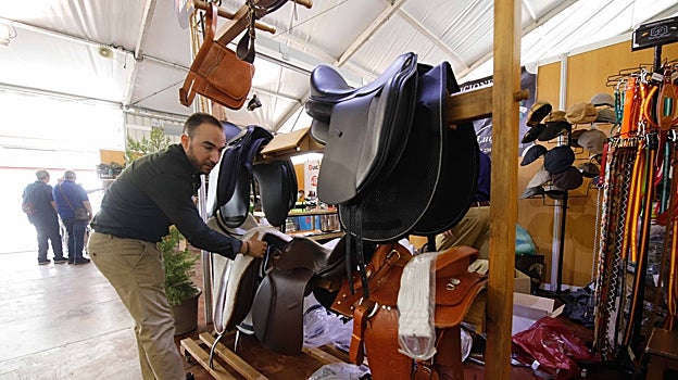 Una persona coloca sillas de montar en un expositor