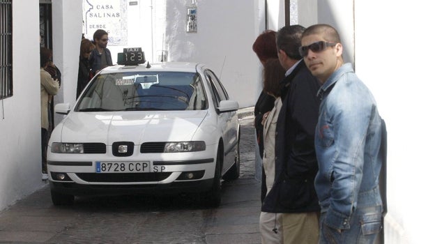 Varios viandantes esperan en una pequeña acera a que pase un taxista en el Casco de Córdoba