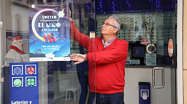 Un lotero del Centro de Córdoba, hoy colocando el cartel del sorteo de El Niño