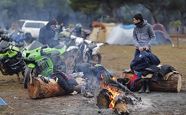 Motoristas calentándose en una hoguera en la campa
