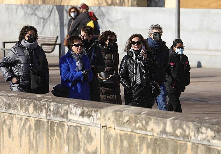Viandantes en Córdoba protegiéndose del frío