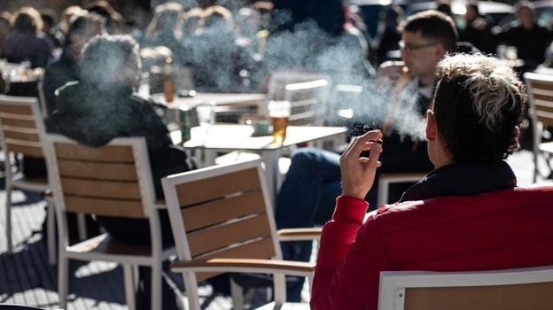 Un joven fuma en una terraza