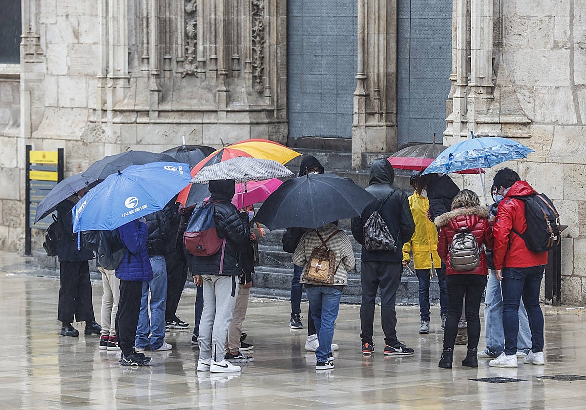 Un grupo de turistas se resguarda de la lluvia en el centro de Valencia