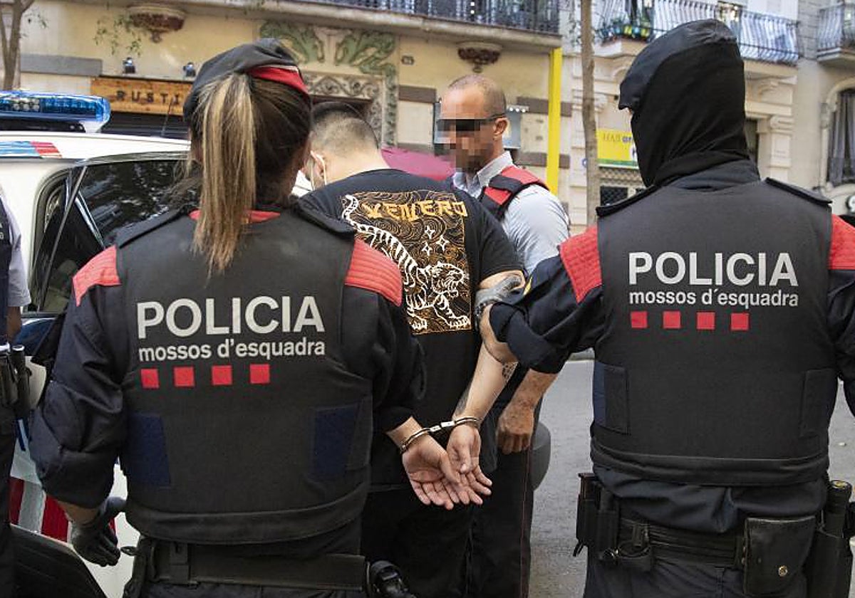 Agentes de los Mossos d'Esquadra trasladan a un detenido