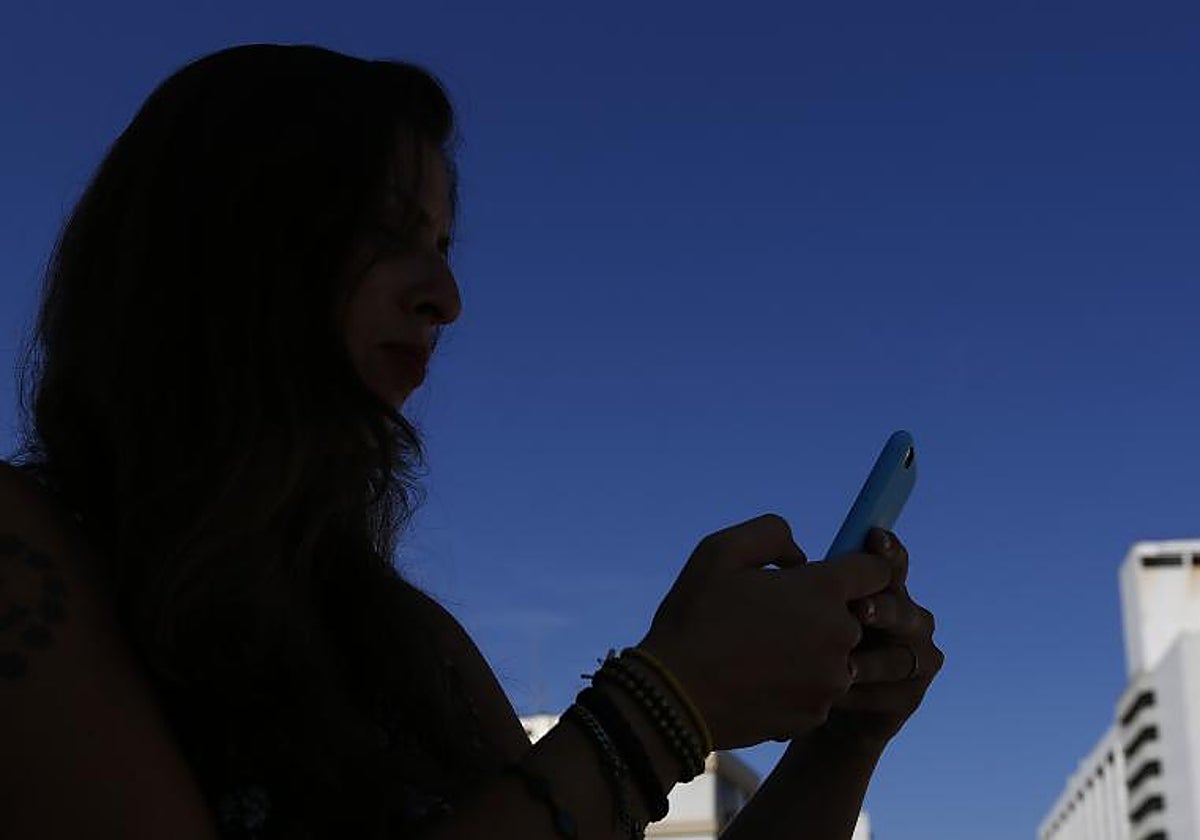 Una mujer mira a su teléfono móvil