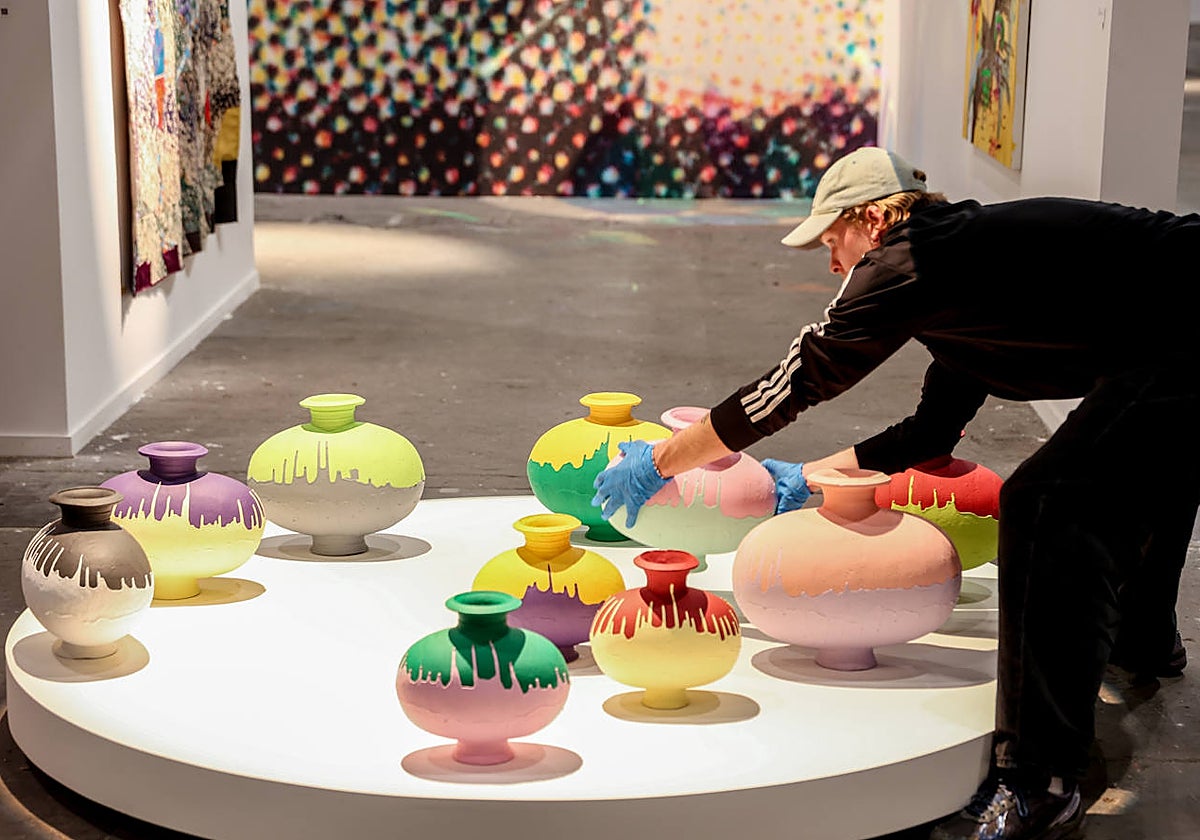 Una persona coloca un jarrón dentro de una galería