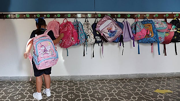 Una niña cuelga su mochila en una percha de un colegio