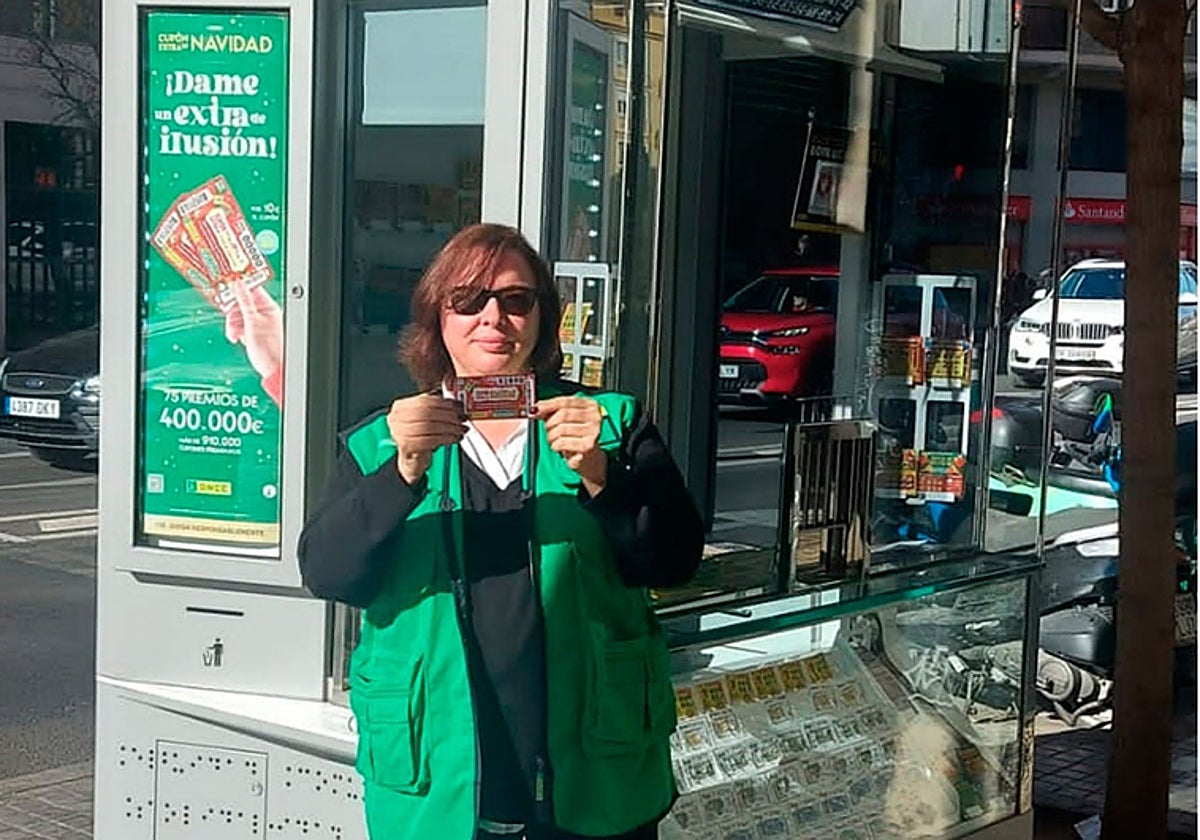 Nieves Ramos, con el número premiado junto a su quiosco, en una imagen difundida por la ONCE en sus redes sociales