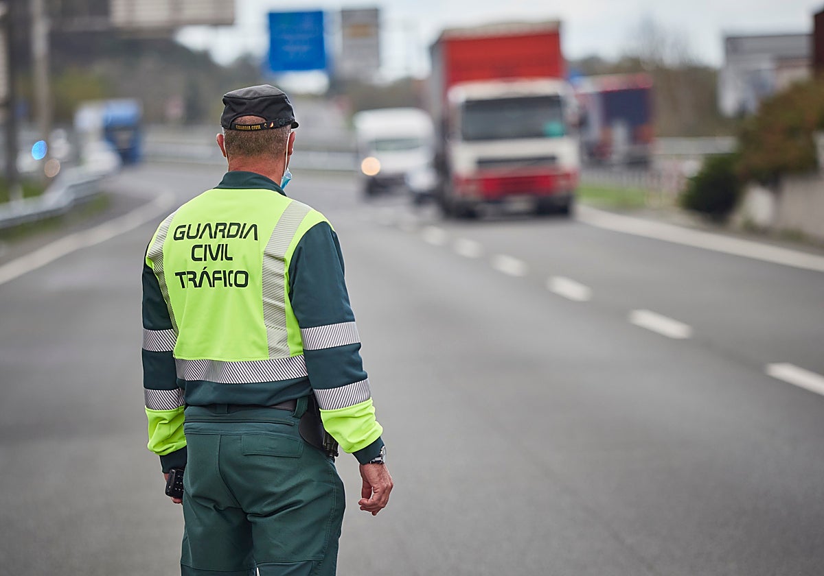 Un agente de la Guardia Civil patrulla en una carretera por donde pasa un camión