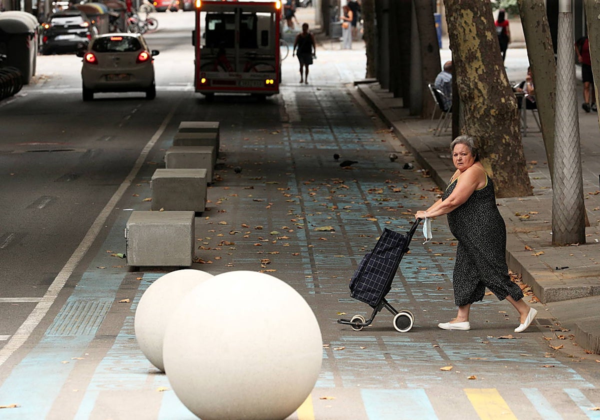 Una mujer atraviesa una zona con elementos de urbanismo táctico en el Eixample de Barcelona