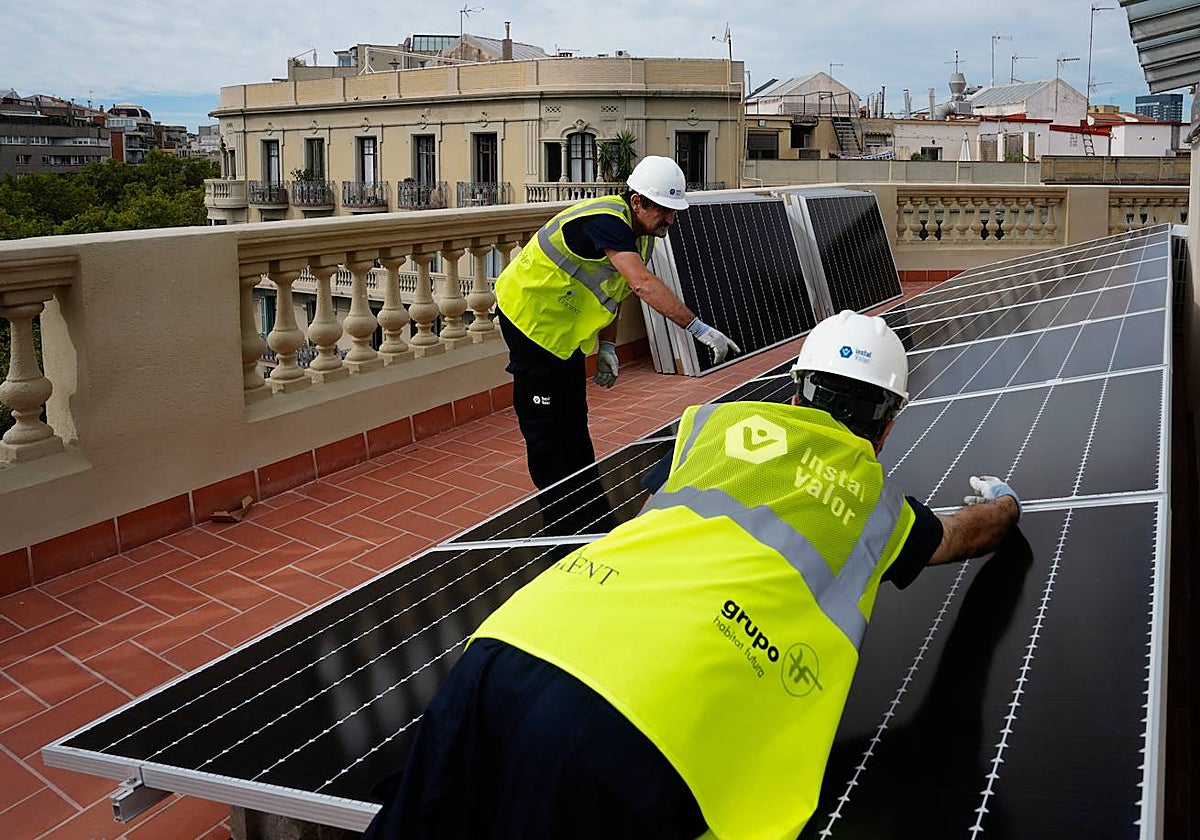 Dos operarios de placas solares colocan una instalación en la azotea de un edificio