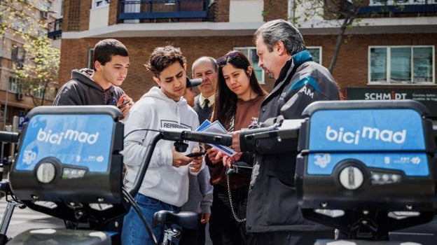 Un informador municipal explica a varios jóvenes cómo darse de alta en la aplicación