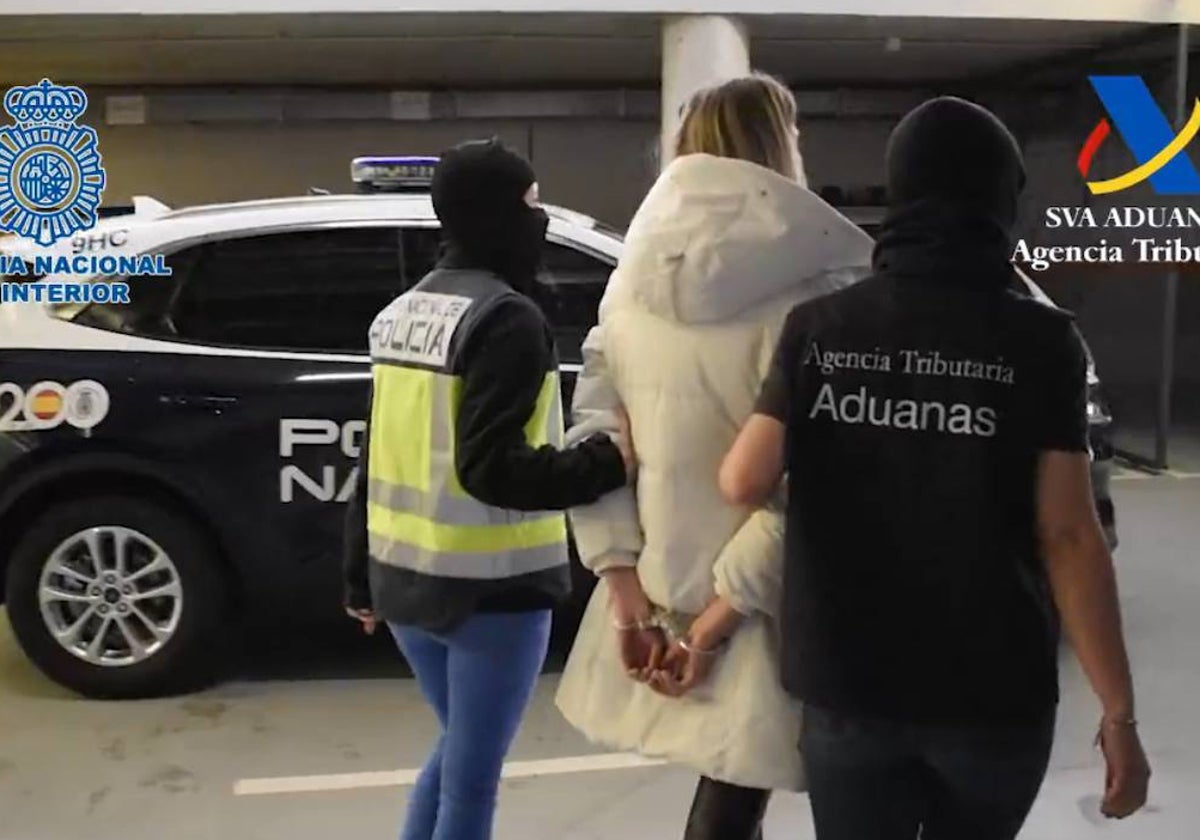 Momento en que dos agentes detienen a la presunta cabecilla de la trama