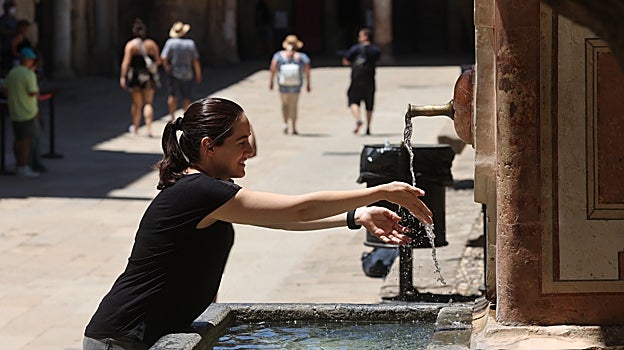 Una joven se refresca en el Patio de los Naranjos