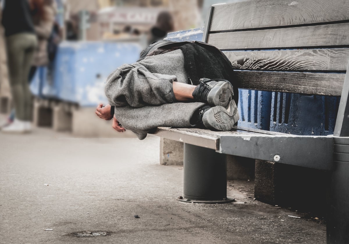 Una persona sin hogar duerme en un banco, en una imagen de archivo
