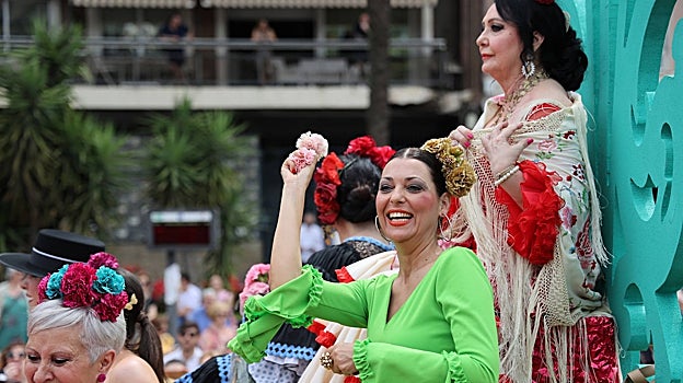 Una mujer lanza claveles desde una carroza