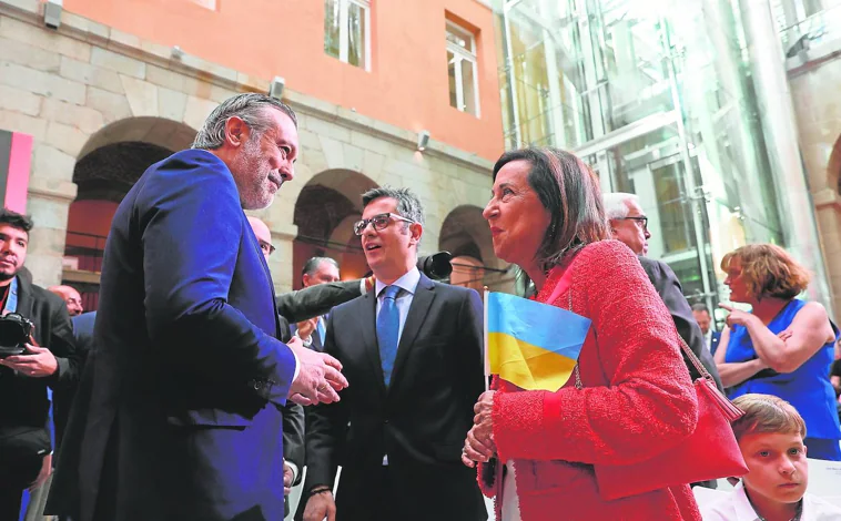 Imagen principal - 1. Los ministros de Presidencia y Defensa llegaron juntos a Sol. Bolaños, con Enrique López en la foto, tenía asiento reservado pese a no estar invitado // 2. El saludo de Isabel Díaz Ayuso a Bolaños fue rápido y frío. El ministro solo tuvo tiempo de cogerle un momento el brazo // 3. El ministro, que se ausentó unos minutos durante el discurso de Ayuso, acusó al Gobierno regional de «crispar» y provocar una polémica «artificial».