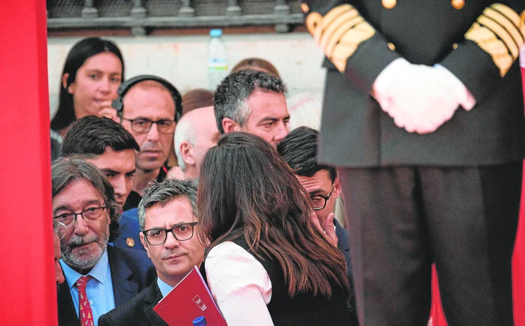 Imagen principal - 4. Cuando intentó acceder a la tribuna de autoridades, la jefa de protocolo de la Comunidad cortó el paso al ministro, pese a su insistencia // 5. El ministro tuvo que presenciar la parada cívico-militar fuera de la tribuna. Al cruzarse después Ayuso, la frialdad se intuyó con claridad // 6. La ministra de Defensa participó en la ofrenda floral. Bolaños, no. Ambos, junto al diputado regional José Cepeda, al marcharse de Sol.