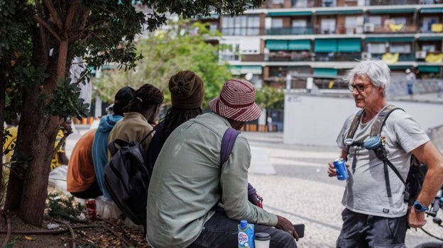 Lander (derecha), junto a sus amigos, en la plaza de Arturo Barea de Lavapiés; al fondo, los balcones lucen banderas amarillas en señal de protesta por la inseguridad y la droga en el barrio