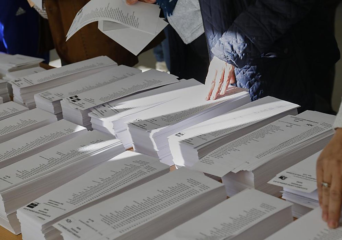 Imagen de una mesa con papeletas de diferentes partidos políticos durante unos comicios en un colegio electoral de Sevilla