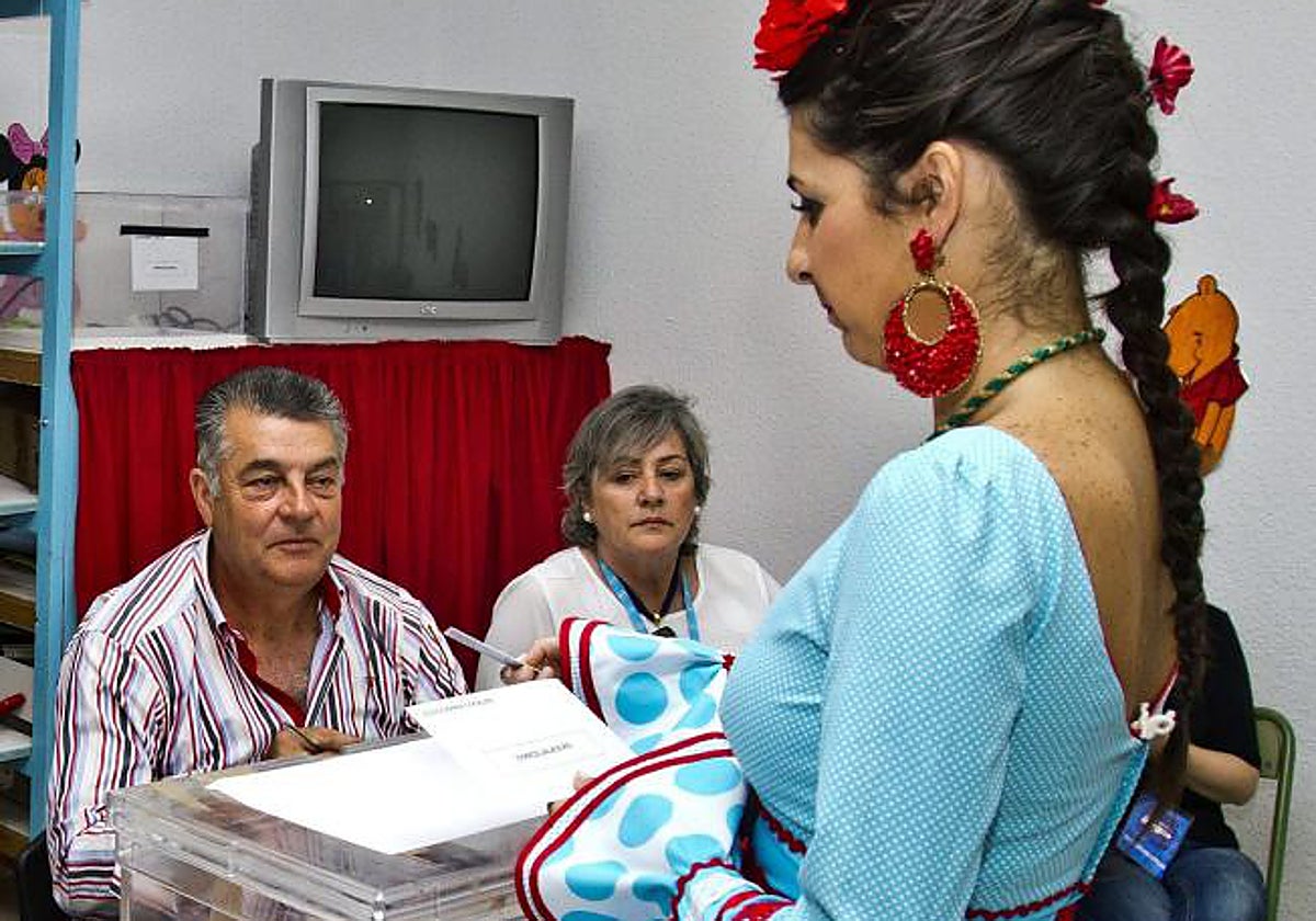 Una mujer vestida de flamenca votando en El Rocío en los comicios de 2015