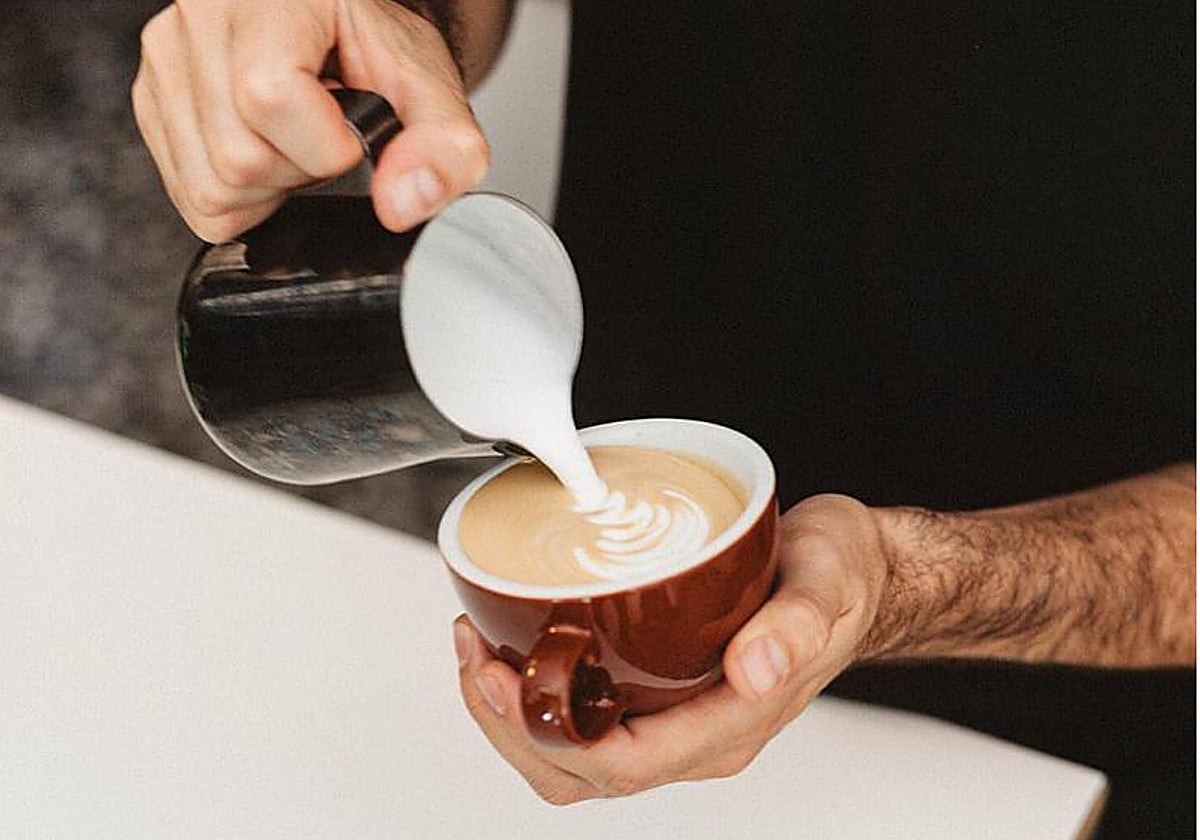 Imagen de archivo de un camarero sirviendo una taza de café